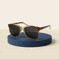 Lunettes à trous Ophtalgym vues de trois quarts sur un socle bleu encre, fond crème